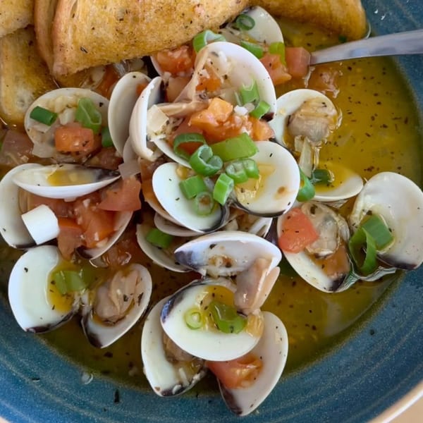 Steamed clams in a rich broth with diced tomatoes, green onions, and toasted bread.